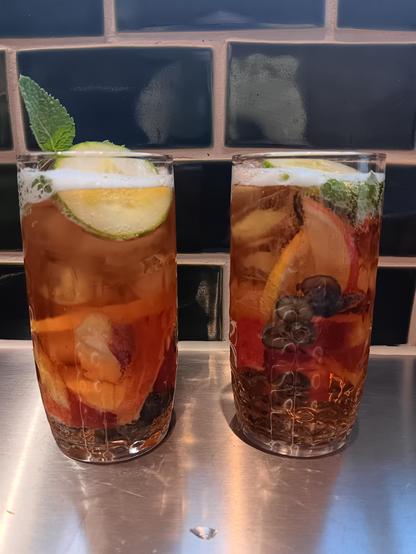 To glasses of Pimm's and lemonade with a bunch of fruit. 