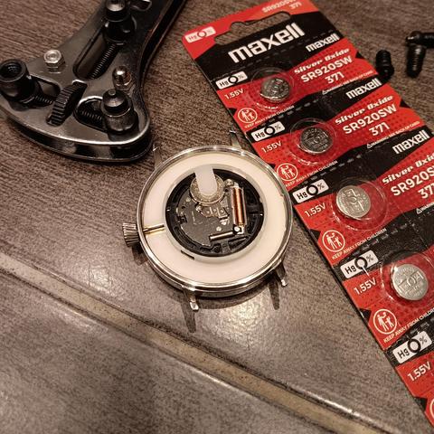 Watch with the back removed with batteries and case removing tool nearby. 