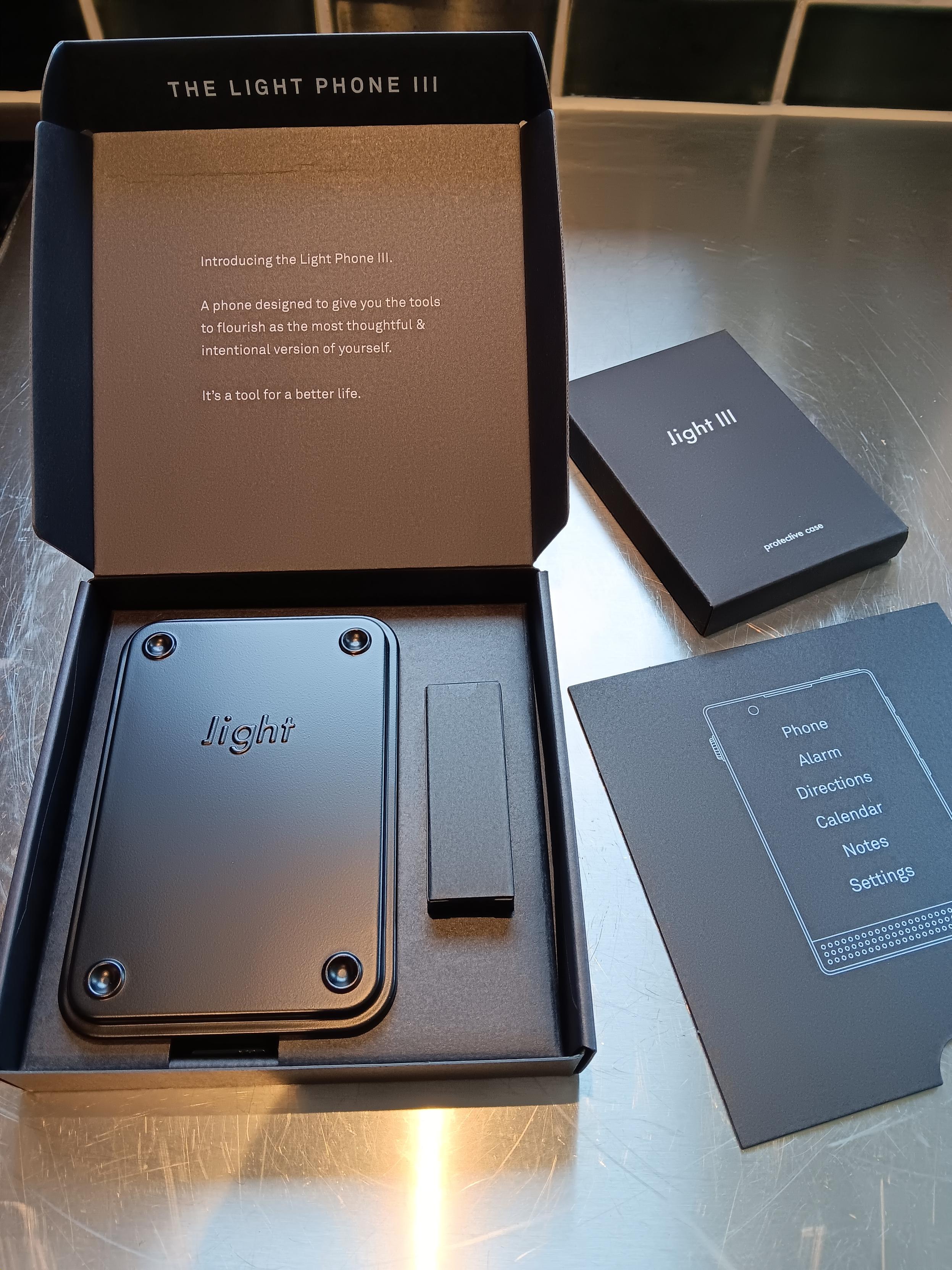 Lightphone packaging opened to reveal a meta tin and various info about the product.
