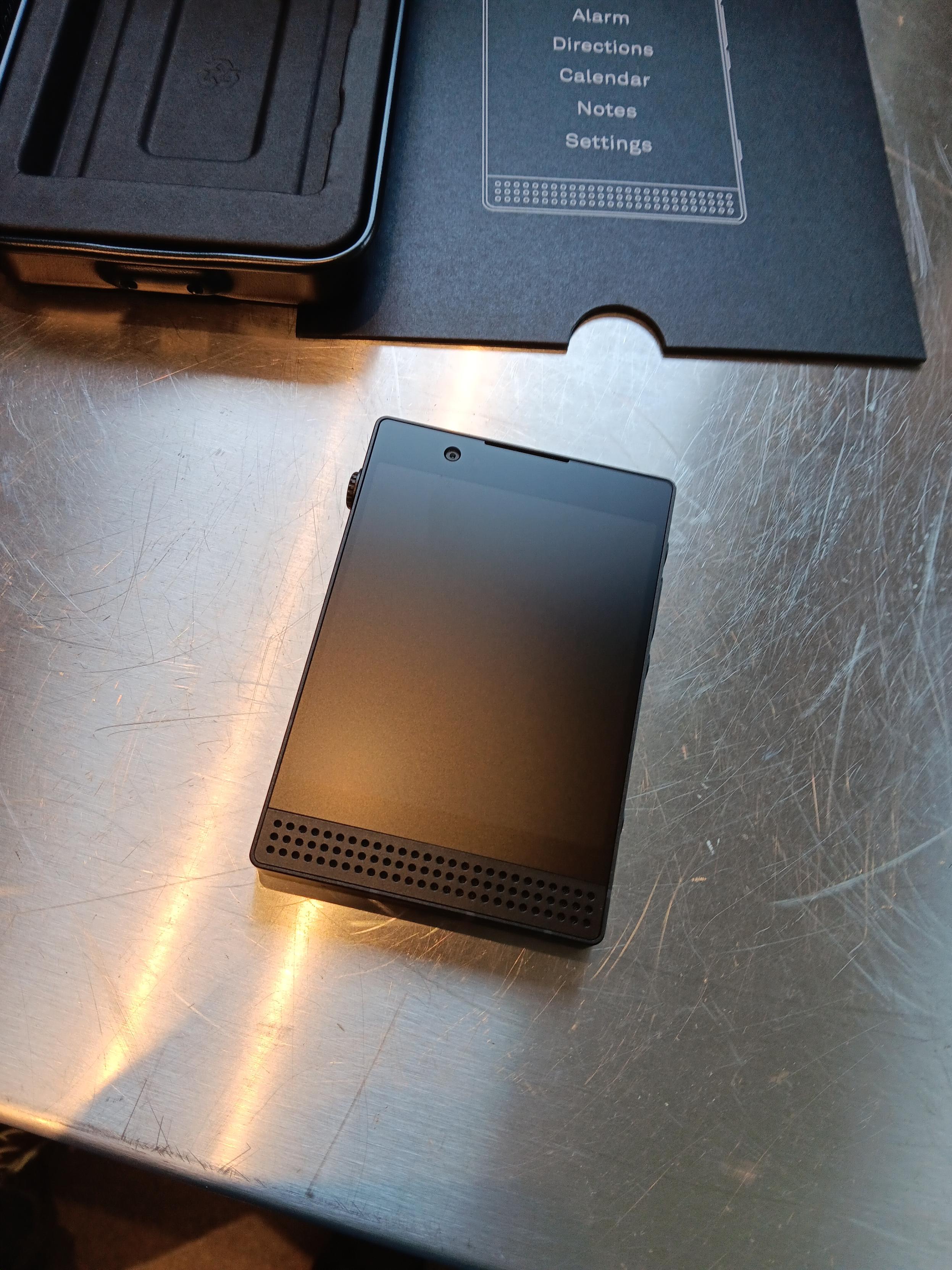 The lightphone with its distinct I've speak grill next to its packaging.