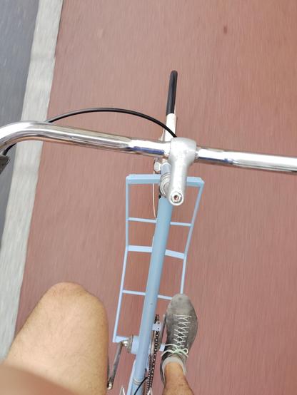 A view looking down at a tallbike from the position of the rider. It is a long way to the ground.