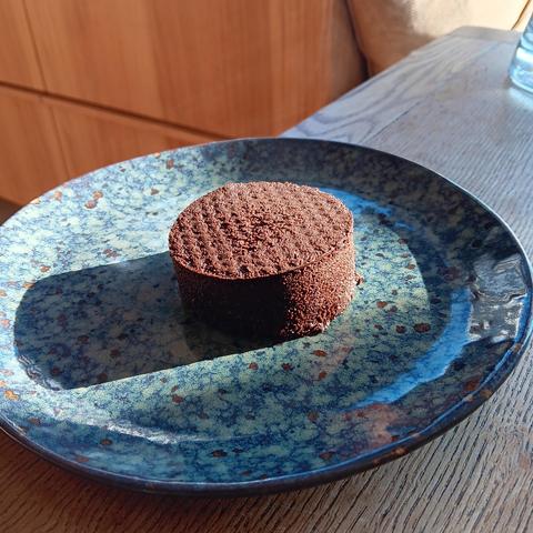 A coffee 'puck' sitting in the centre of a small plate. 