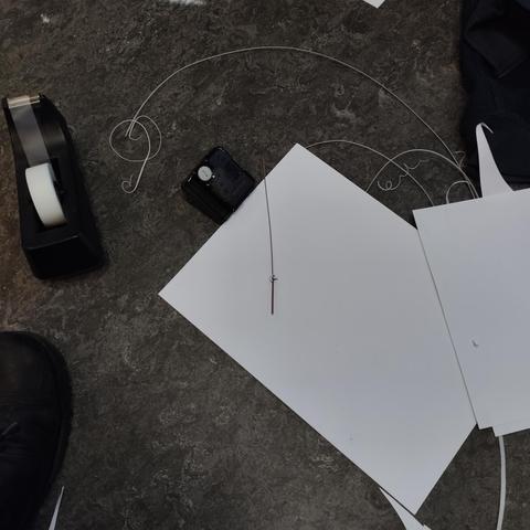 Various things on the ground, cellotape, a clock movement, a hand from a wall clock, cut up paper