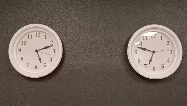 Two clocks showing the time 5:11 but the right one is ticking in reverse.