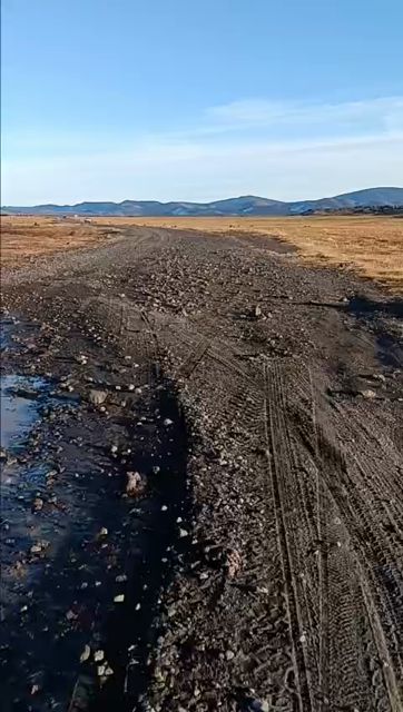 Man riding a black gravel road from the rider's perspective, panning around at the Icelandic scenery. The camera pans down a couple of times to show that a unicycle is being ridden. 