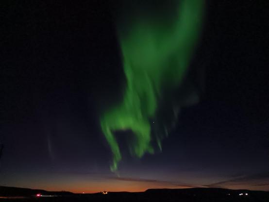 A large amount of green in the night sky above a very late sunset. 