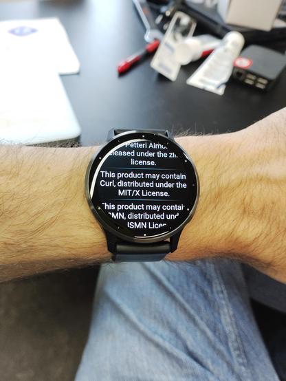 A Garmin Venu 3 watch on wrist showing the about page information, which includes the line, "This product may contain Curl, distributed under the MIT/X License."