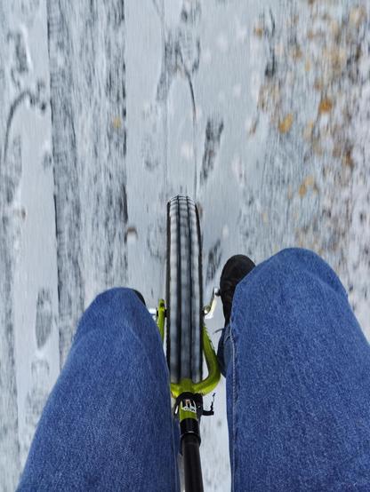 Looking down at a unicycle from the rider's perspective. There is a very light dusting of snow on the ground.