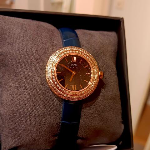 Golden colour watch with lots of small (glass) 'jewels' around the outer edge. The face is dark blue as is the strap. 