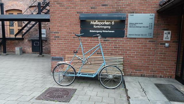 Blue "tallbike" (seating position is high from the ground) in front of a building