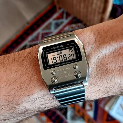 Skmei digital watch with a squared off octagonal metal case. It has a two line LCD display at the top and four buttons below. 