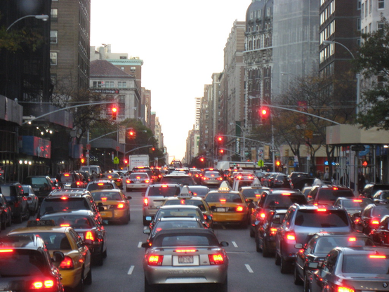 A highly congested road in a city. Many cars viewed from behind with their red lights glowing