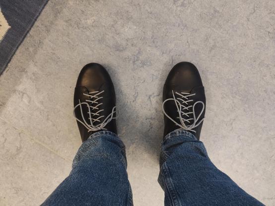 Looking down at my shoes which are black with gray laces.