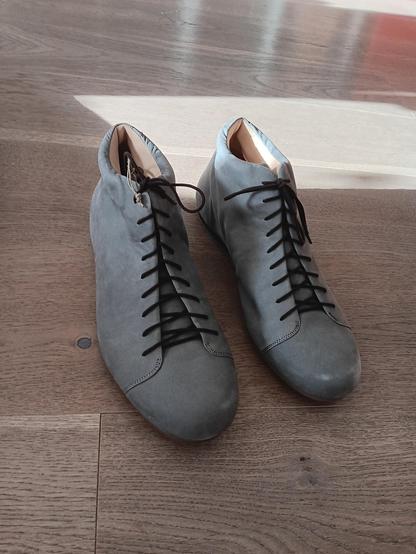 Gray boots with black laces on a wooden floor