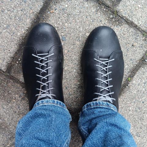 Black shoes with very long, grap shoelaces tucked into the shoes