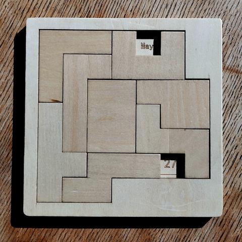 A wooden, calendar puzzle with the date set to the 27th of May.