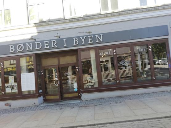 A skewed picture of a store front with a large glass window. Somewhere in the middle is a reflection of a person unicycling.