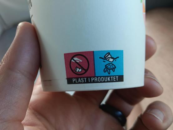 Cup plastic warning showing icons that indicate the product contains plastic and that improper disposal can harm marine life, illustrated by a crossed‑out hand holding plastic and a turtle affected by plastic waste.