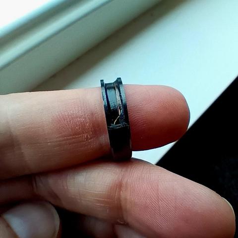 Broken black ring resting on my finger with exposed wires. 