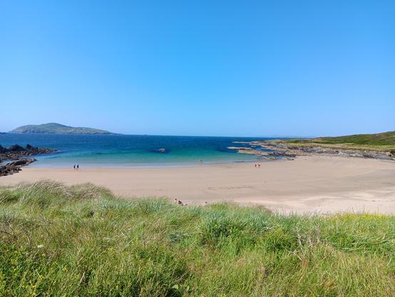 Sandy beach, blue green water, clear blue sky. 