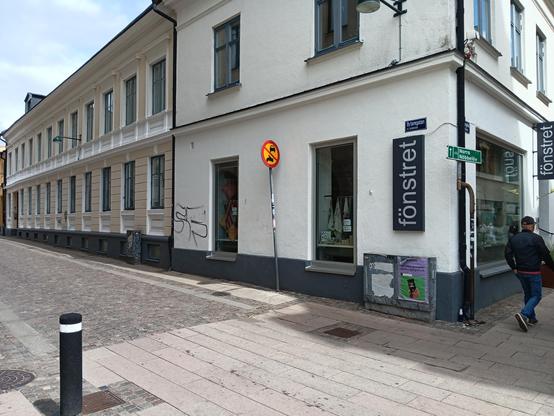 A regular street. A sign on the side of a store reads fönstret. 