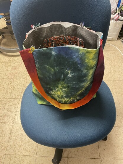 The other side of the bag with a big green and yellow spiral.  The strap is warm orange purple and raspberry.  Inside you can see a pocket made with rainbow wave fabric. 