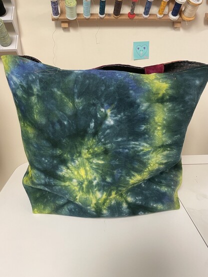 Unobstructed view of green/blue/yellow swirl dyed canvas side of the tote bag.