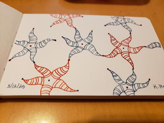 Hand drawn generative/procedural art in ink on an open page of my sketchbook. The abstract pattern looks a bit like a network diagram made with sea stars.