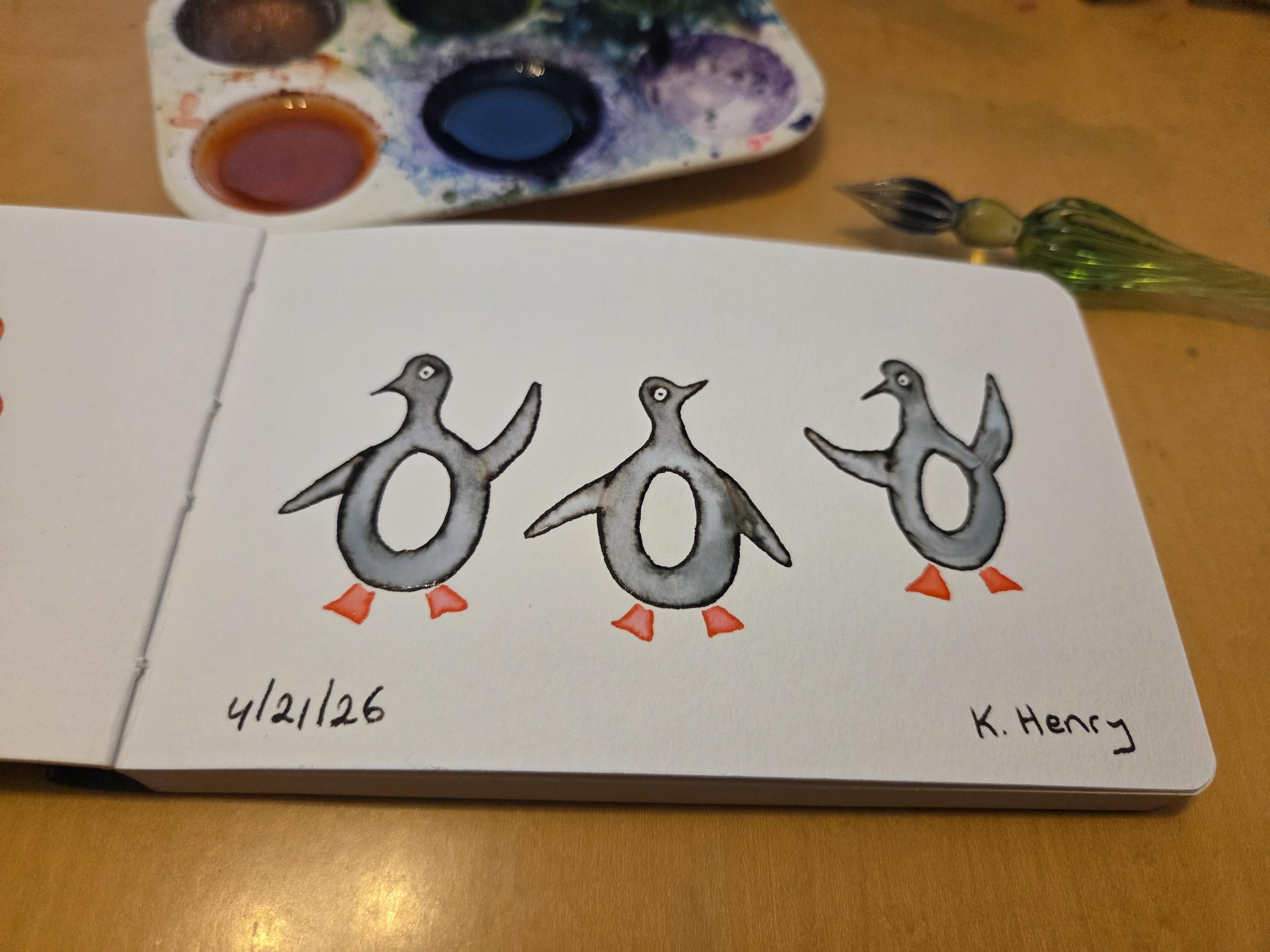 Hand drawn generative/procedural art in ink on an open page of my sketchbook. The abstract pattern looks like three penguins, with attitude. My glass dipping pen an inks are next to my sketchbook.