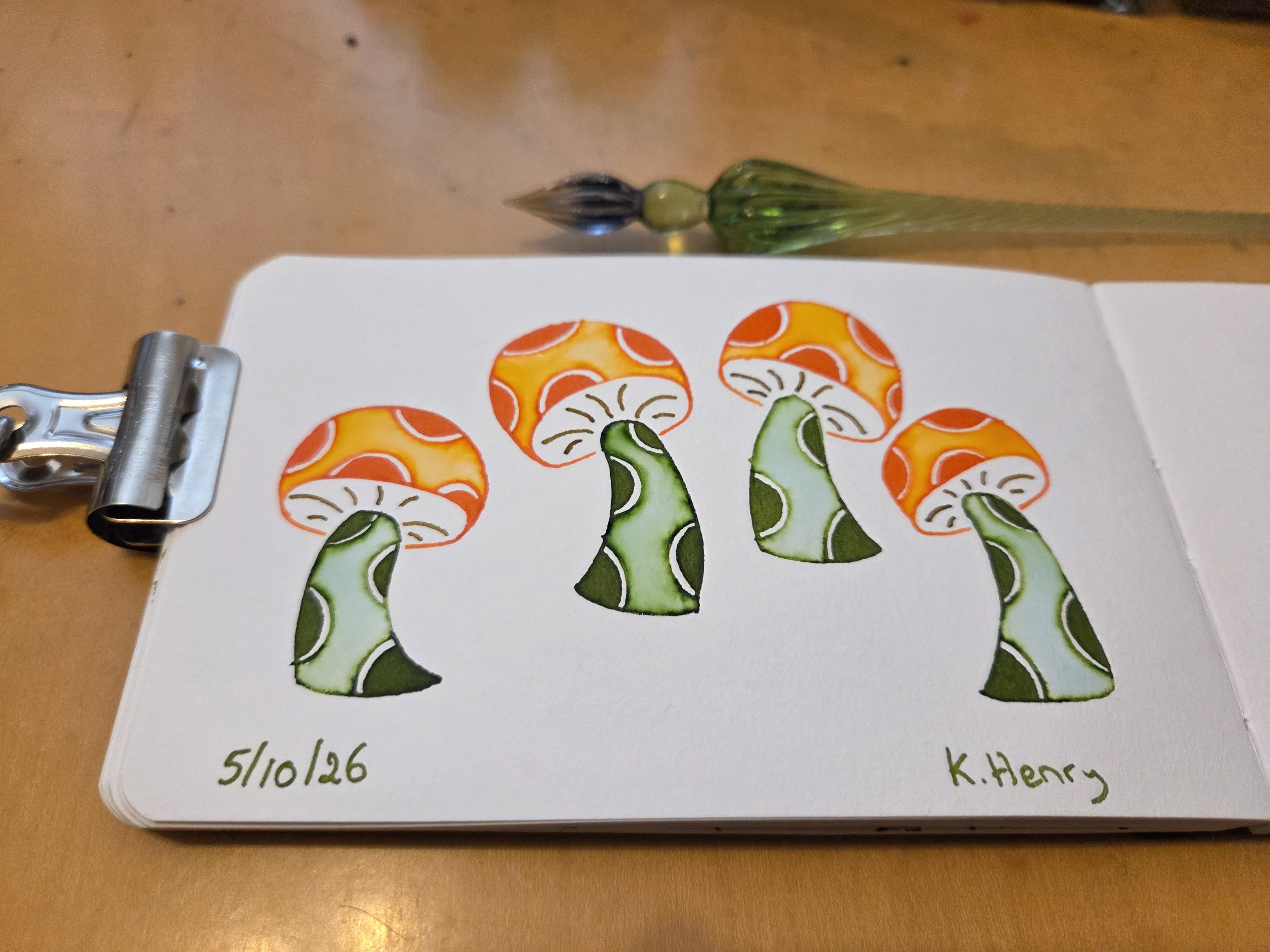 Hand drawn generative/procedural art in ink on an open page of my sketchbook. The abstract drawing has mushroom motifs, with polka dots on their stems and caps. A binder clip is holding my sketchbook open, and my glass dipping pen is above it.