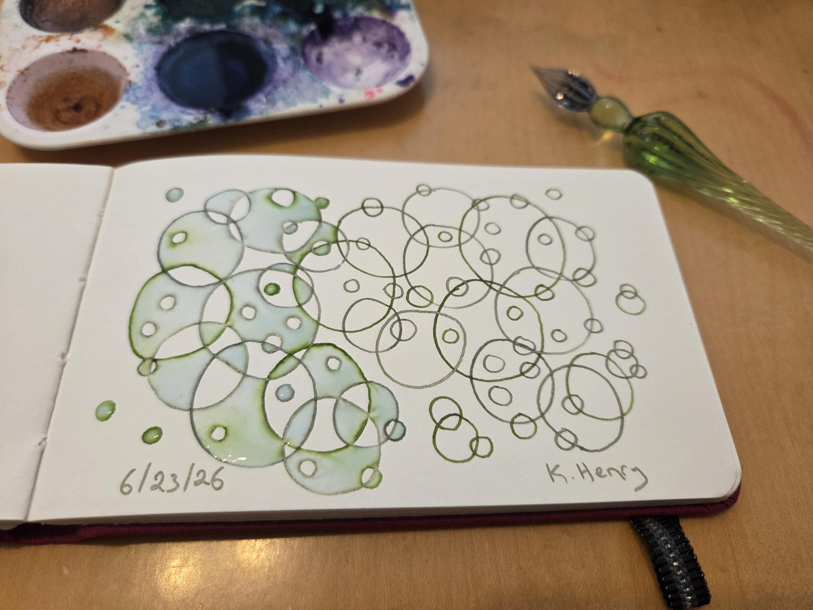 Hand drawn generative/procedural art in ink on an open page of my sketchbook. The abstract pattern is inspired by algae but is just a bunch of overlapping circles of varying sizes. The result is quite pretty, if I may say so.