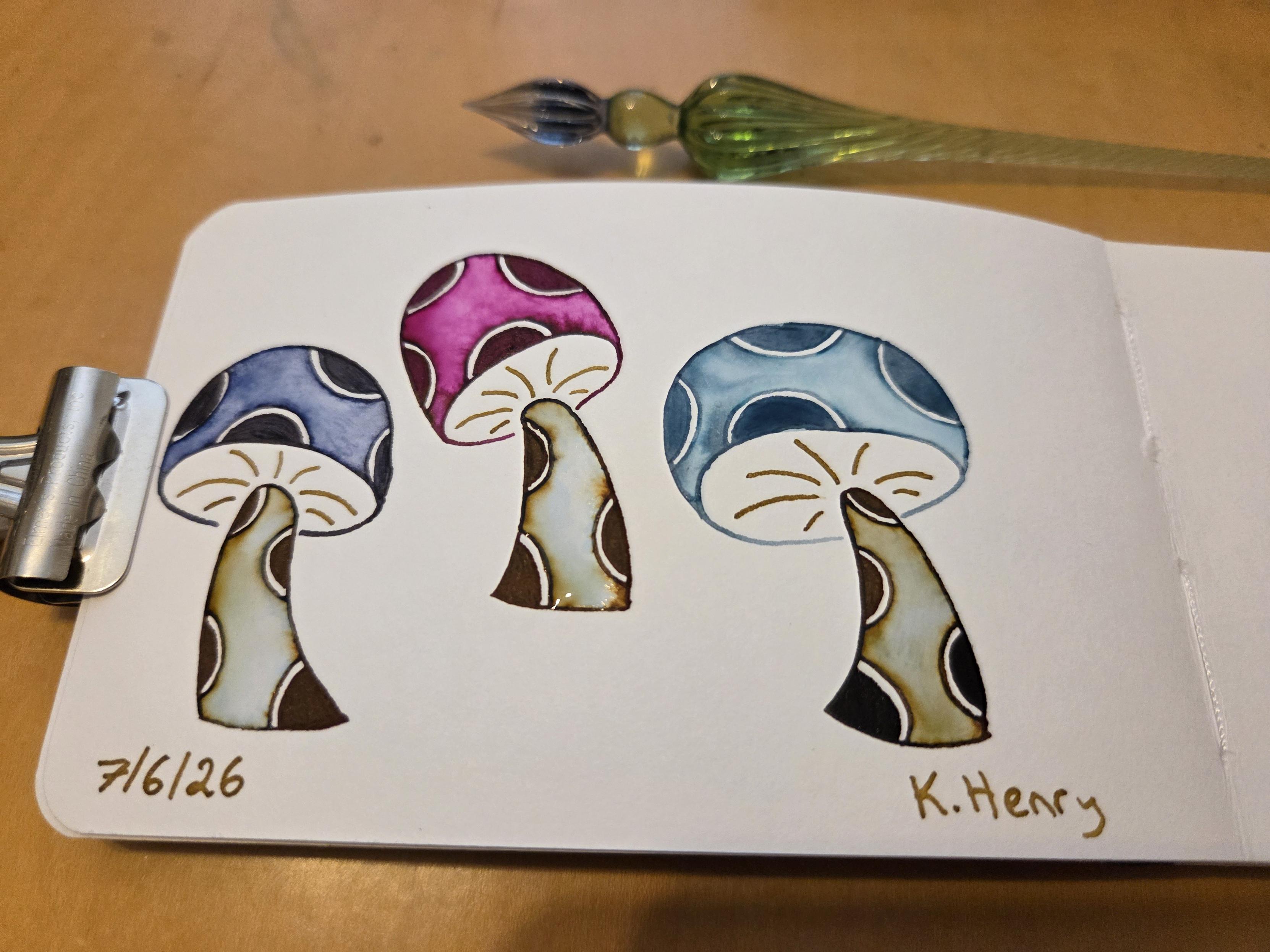 Hand drawn generative/procedural art in ink on an open page of my sketchbook. The abstract pattern looks like mushrooms with polka dots on the stems and caps. There is a clip holding the pages open, and my glass dipping pen is next to my sketchbook.