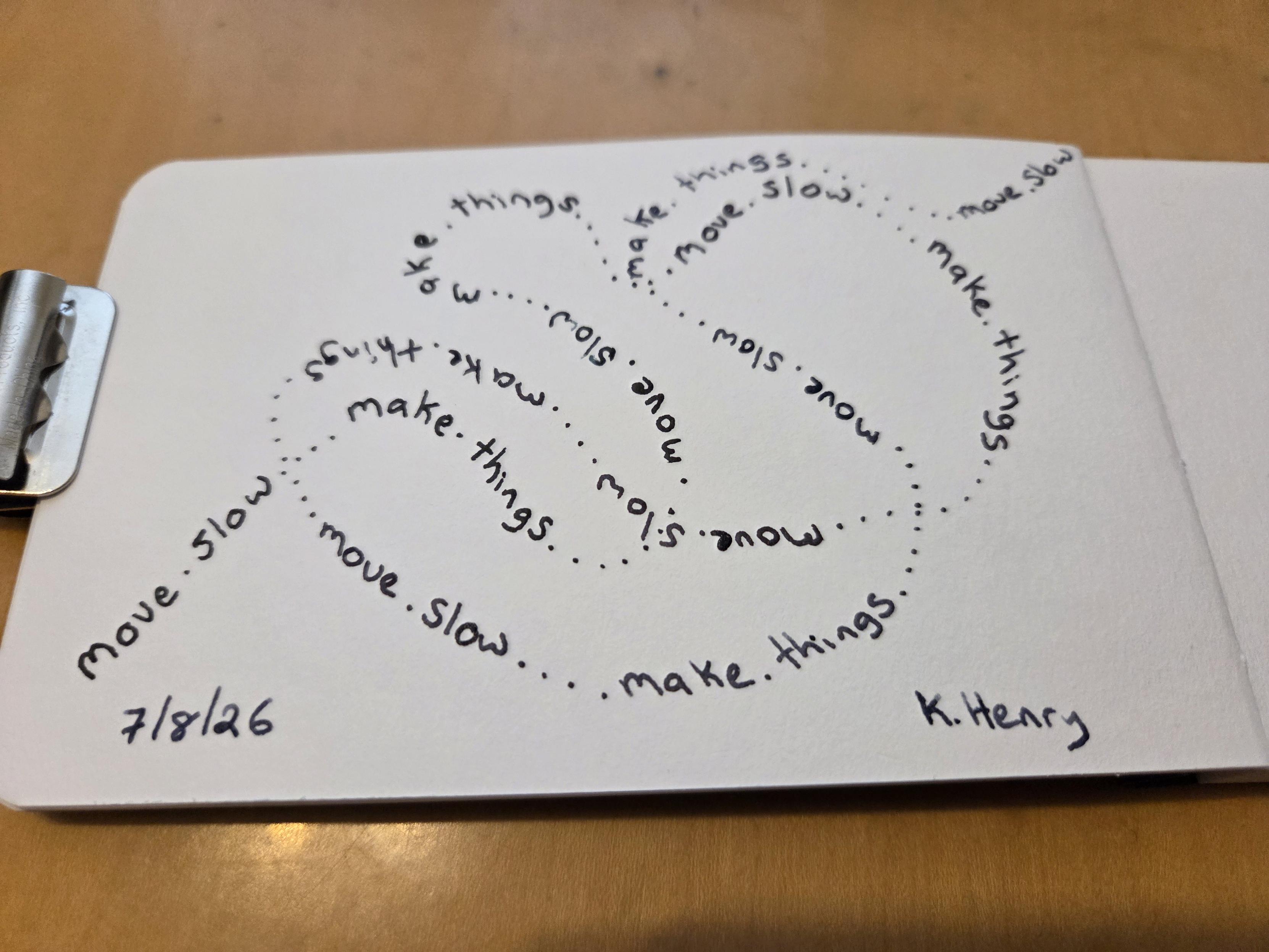 Hand drawn generative/procedural art in ink on an open page of my sketchbook. I've drawn a meandering line of text that circles back and loops over itself. The text repeats "move slow. make things."