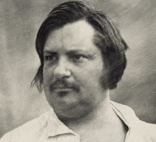 Photographie en noir et blanc d’Honoré de Balzac. Il porte une chemise blanche avec le col ouvert. Ses cheveux sont sombres et mi-longs, légèrement ondulés. Un fond uni et clair met en valeur la silhouette d’Honoré. 