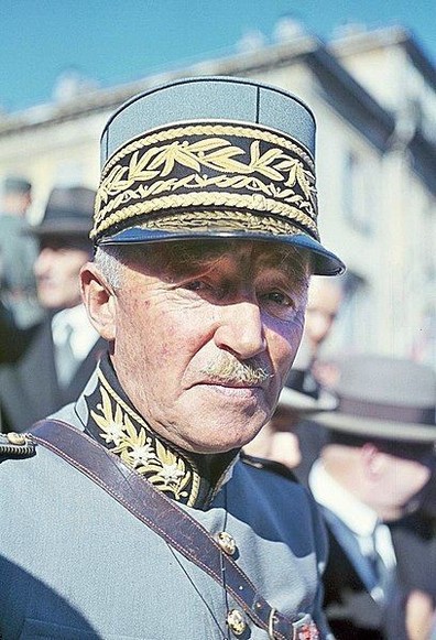 Photo du général Henri Guisan représenté en uniforme militaire. L’accent est mis sur la broderie détaillée de l’uniforme et le chapeau distinctif avec des motifs en feuille d’or. L’arrière-plan est flou pour mettre en valeur la silhouette du général Guisan.