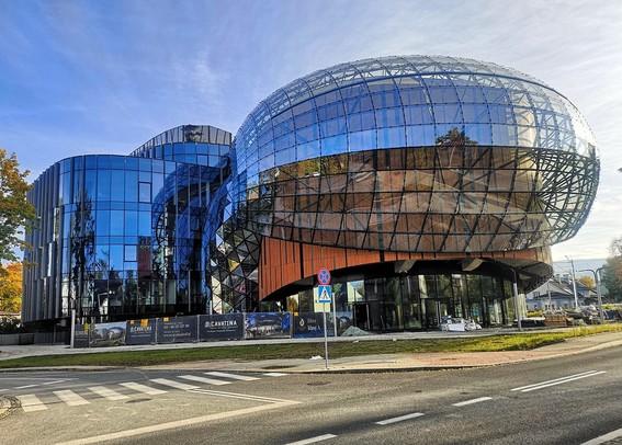 Außenansicht eines Gebäudes mit einer modernen, futuristisch geschwungenen Glasfassade