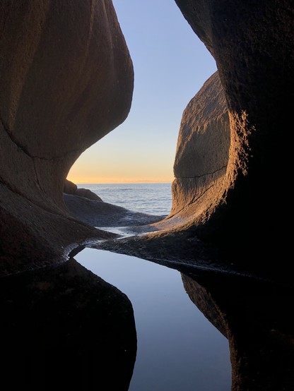 View to the open sea from a pothole whose interior are partially bathed in the light of the setting sun