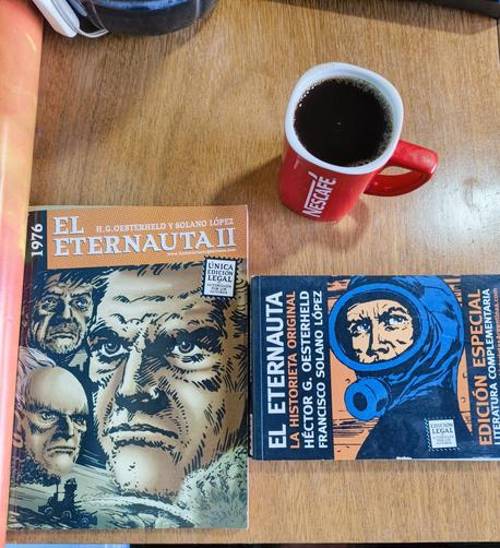 Two copies of El Eternauta comics on my bed table alongside a cup of coffee.