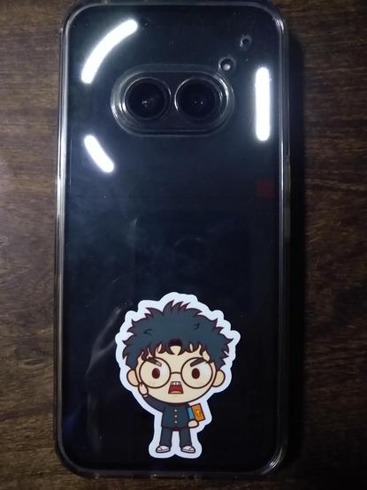 The back of my Nothing Phone 2a, it features a sticker of a chibi Okarun. The glyph lights are illuminated