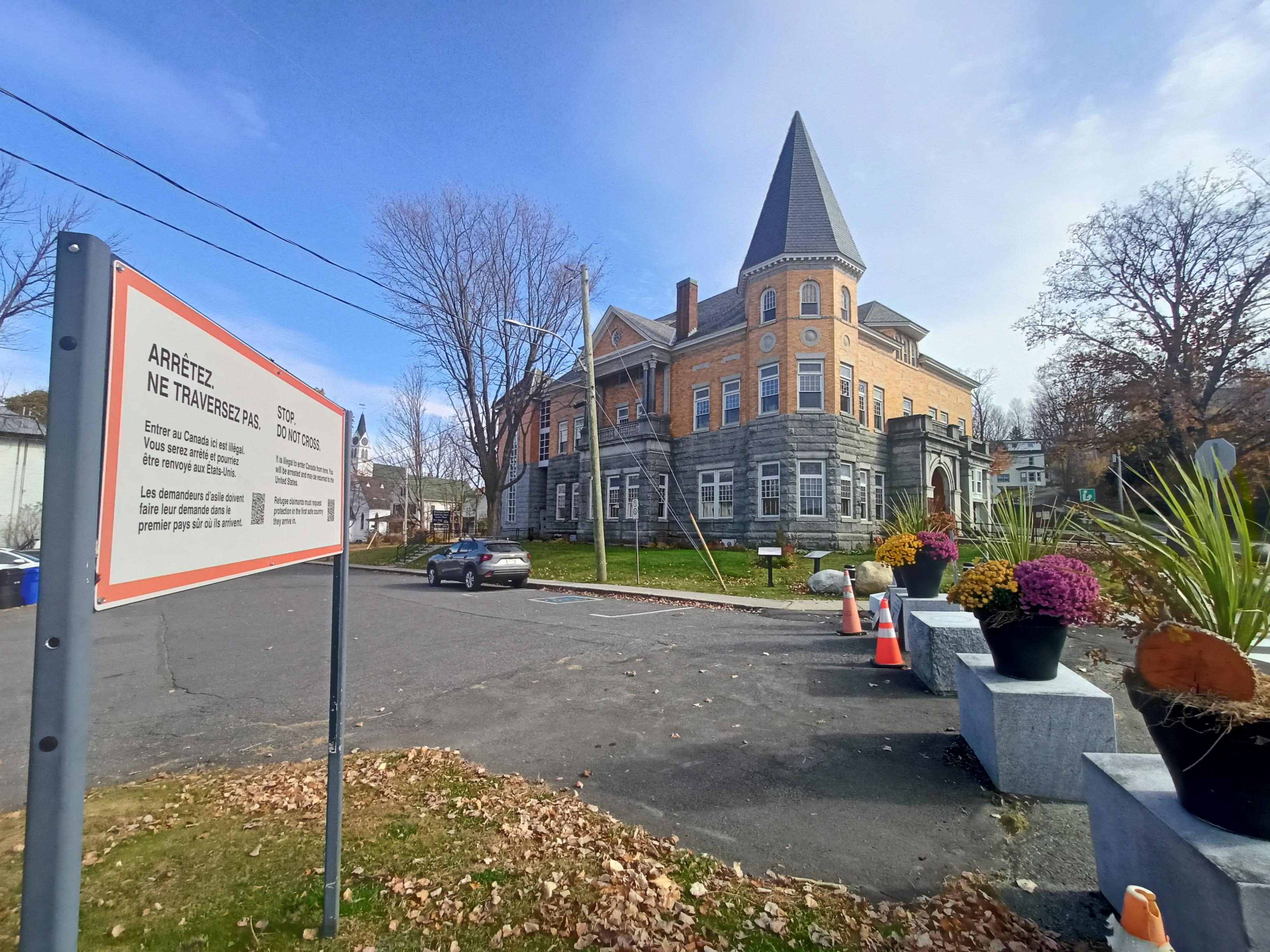 Board "Stop. Don't cross" (in French) at the border, Haskell library 19th building in the background.