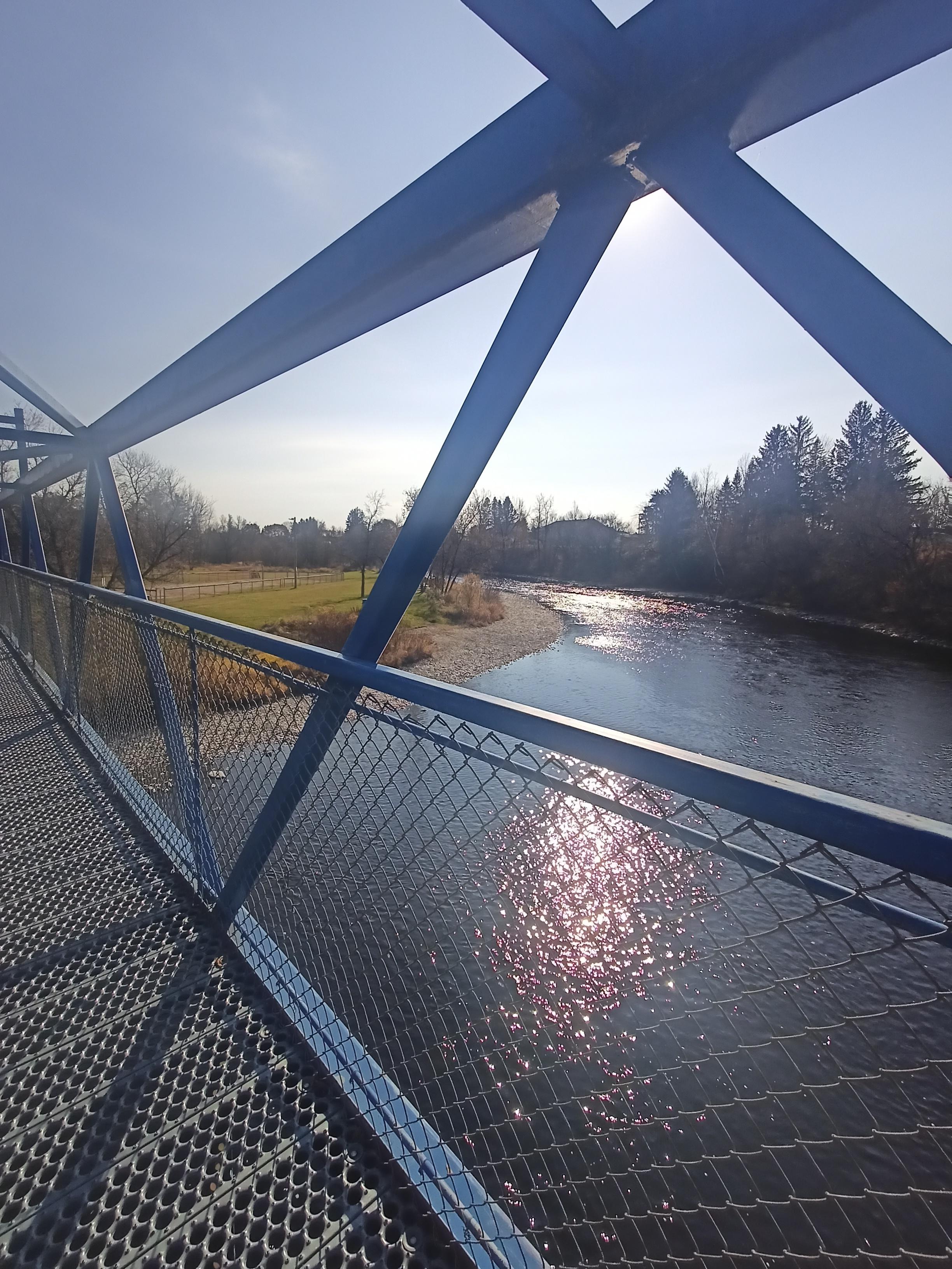 Geometric shapes or a blue brige and its shades, river with reflection of the sun.