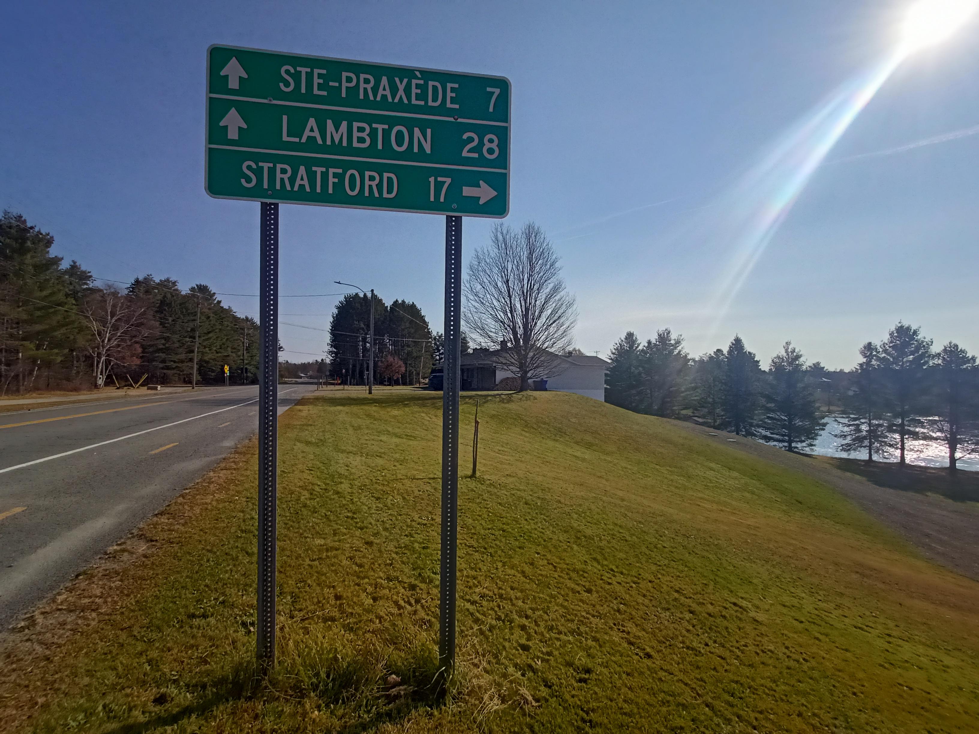 Green directions board by the road, on a green-ish green, a lake on the right (as usual).