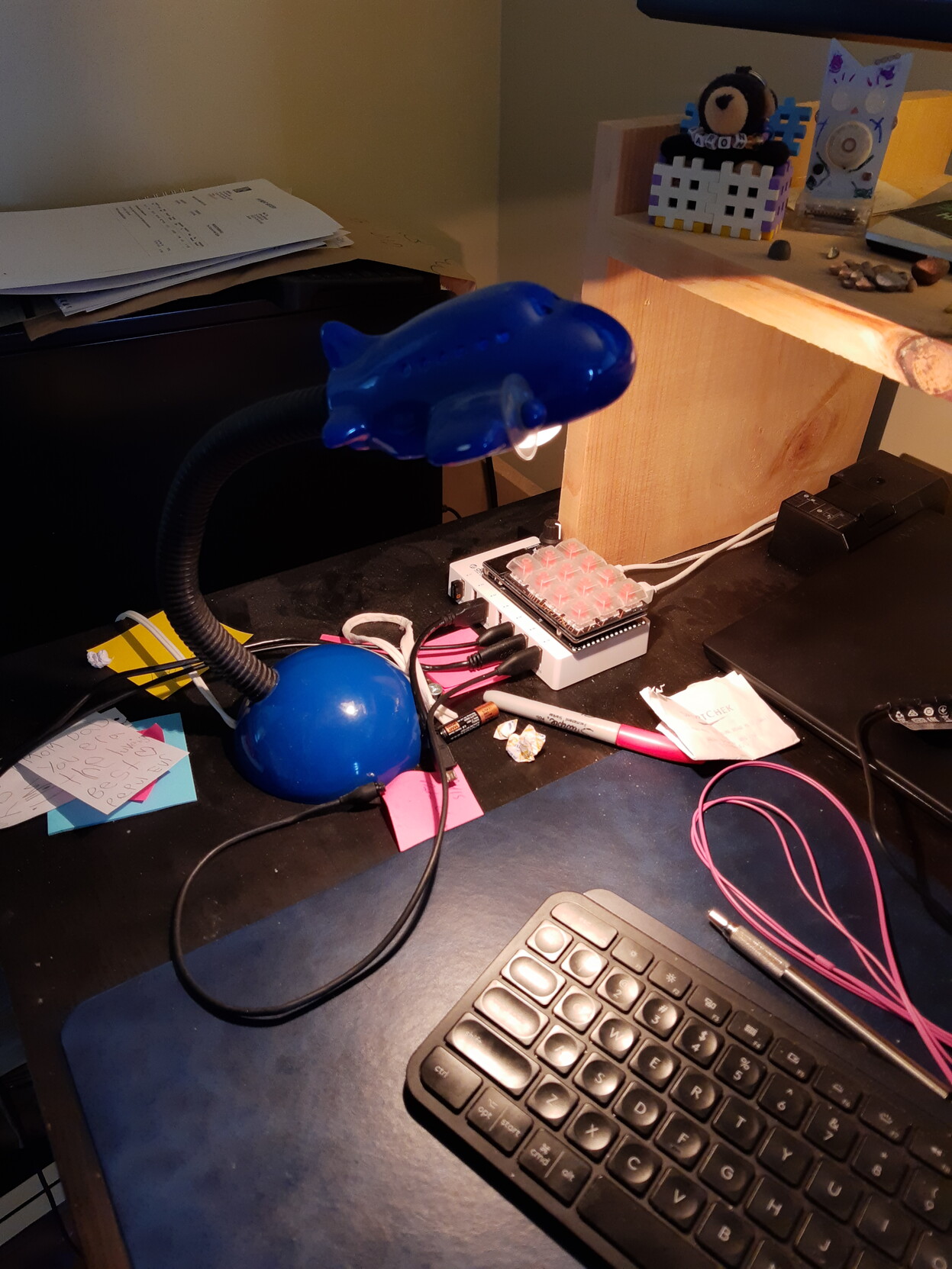 Blue airplane-shaped lamp on a black bendy arm over a blue lamp base. Has a little 25w incandescent bulb in it. It's lighting up my very messy desk.