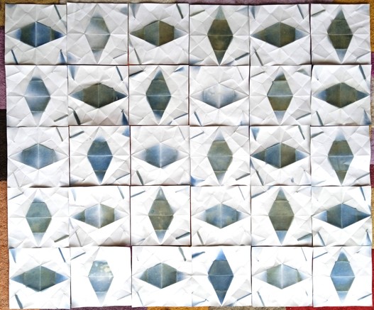 The 30 exposed units, unfolded and developed to present as 30 squares of white paper, each with a diamond of blue-green in the centre and short white lines at the corners. Each differs from all the others to a greater or lesser extent. They are shown in a 6x5 grid, alternating between having the diamond horizontal or vertical.