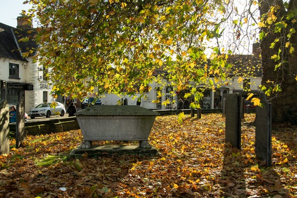 Sunny autumn colours, a stone grave underneath a tree in the churchyard.