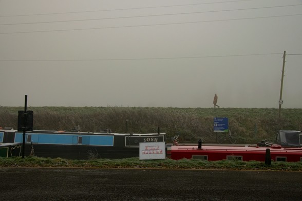 Canalboats and a dyke on a foggy day.