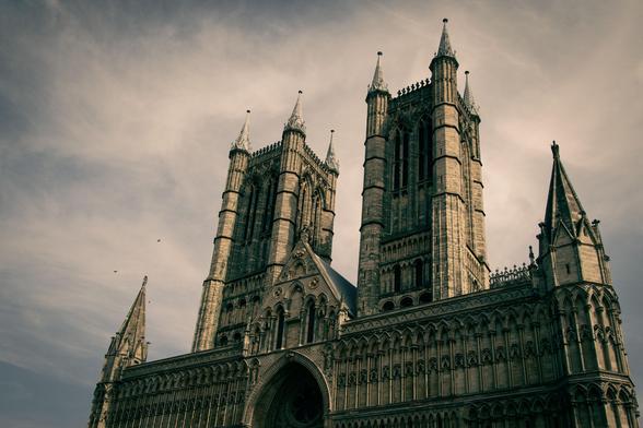 West facade and two spires of a gothic cathedral against a semi-cloudy sky.