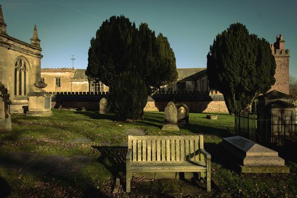 A bench in a sunlit, rustic churchard.