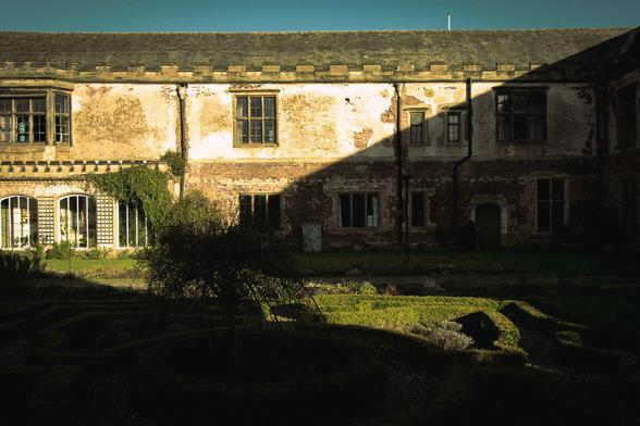 The garden of the old manor house with a strong shadow across the building.
