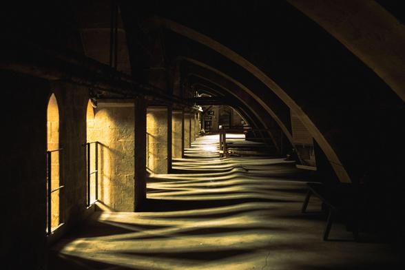 Gallery underneath the arches and roof; light floods in through the arched openings on the left.